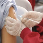 Pharmacist giving a free flu shot in the upper arm at Evergreen Compounding Pharmacy in southwest Calgary